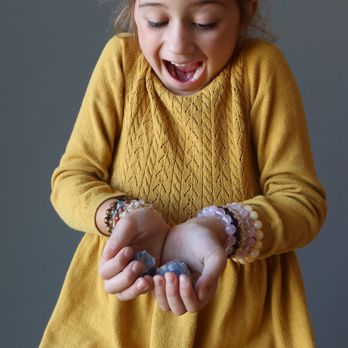 zoe of satin crystals holdinga  one Blue Calcite Raw Gemstone on each hand