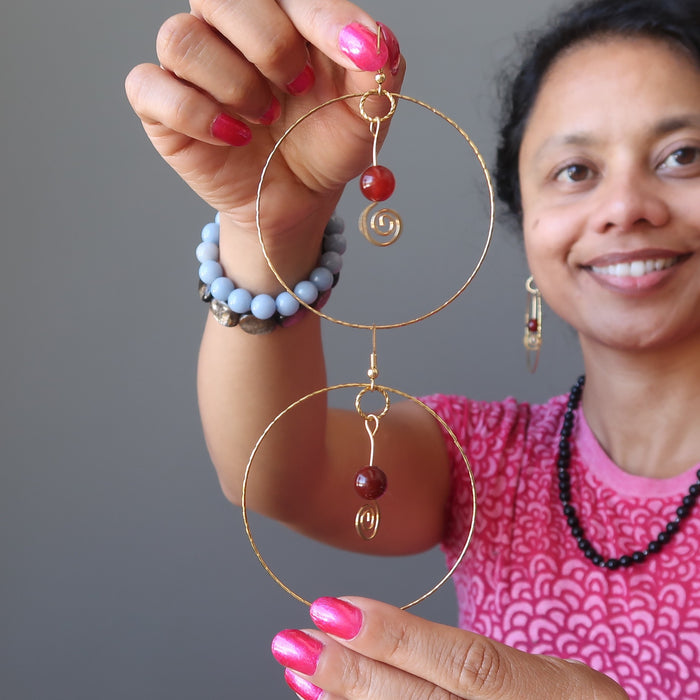sheila of satin crystals holding carnelian hoop earrings