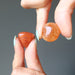 hand holding a carnelian tumbled stones