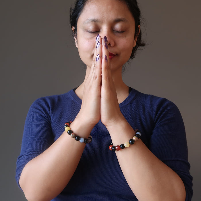 sheila of satin crystals wearing 2 rainbow obsidian and natural chakra stone stretch bracelets with hands in prayer