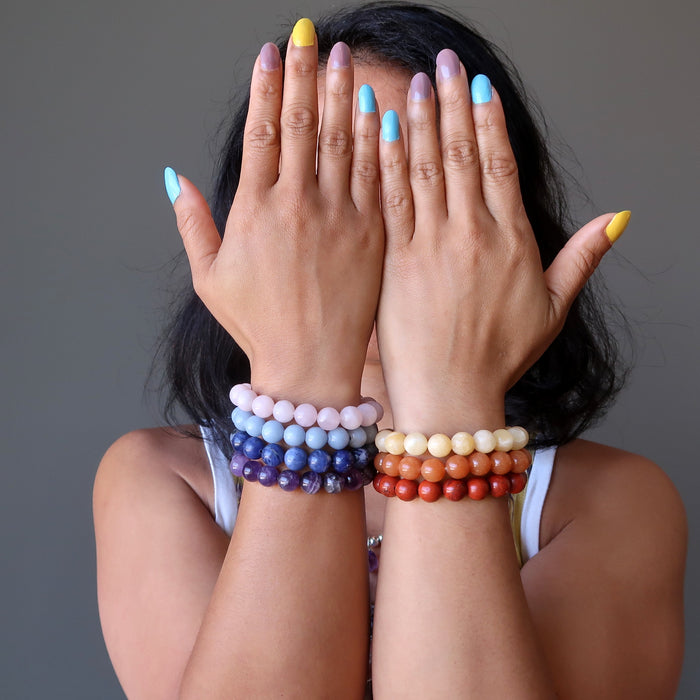 sheila of satin crystals wearing set of 7 chakra bracelets with amethyst, sodalite, angelite, rose quartz, calcite, aventurine and red jasper