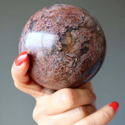 hand holding up chalcedony jasper crystal ball