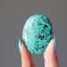 hand holding blue-green and black chrysocolla oval cabochon