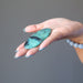 blue-green and black chrysocolla oval cabochon in palm of hand