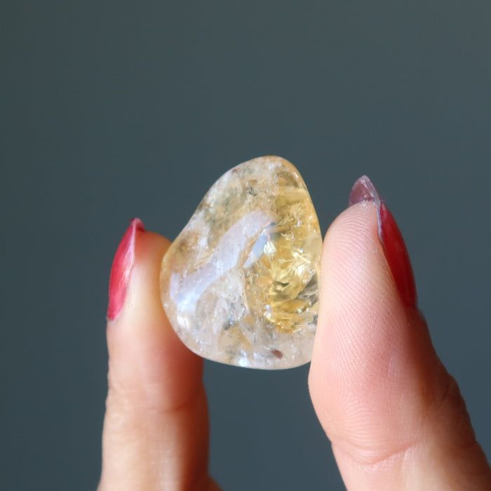 hand holding translucent yellow citrine tumbled stone 