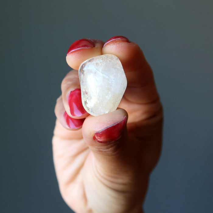 hand holding translucent yellow citrine tumbled stone 