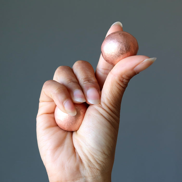 hand holding two Matte Copper Spheres