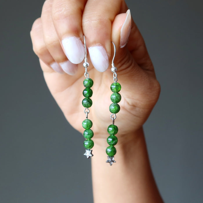 holding green Chrome Diopside dangling on stars sterling silver earrings