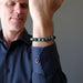 ryan of satin crystals looking at his hand modeling polished emerald stretch bracelet