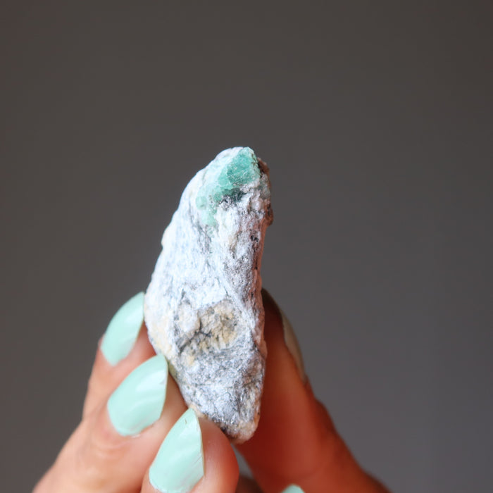 fingers holding raw Emerald Cluster