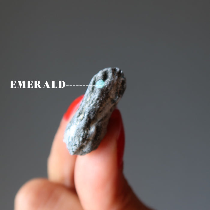 finger tips holding raw Emerald Cluster