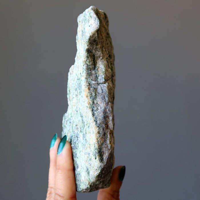 hand holding rough green epidote standing mineral stone