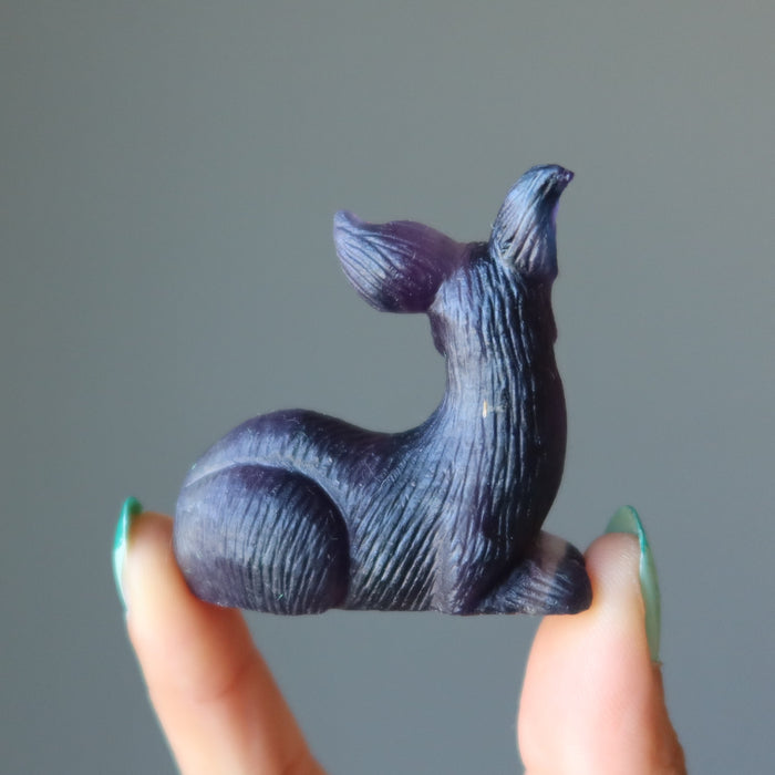 fingers holding displaying side of rainbow Fluorite Deer Figurine