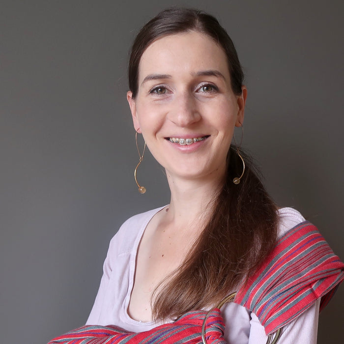 woman carrying her baby wearing golden fluorite earrings