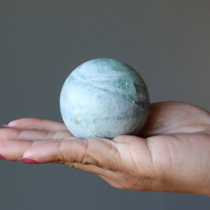holding Creamy Green Fluorite Spheres on the palm