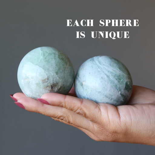 holding 2 Creamy Green Fluorite Spheres on the palm