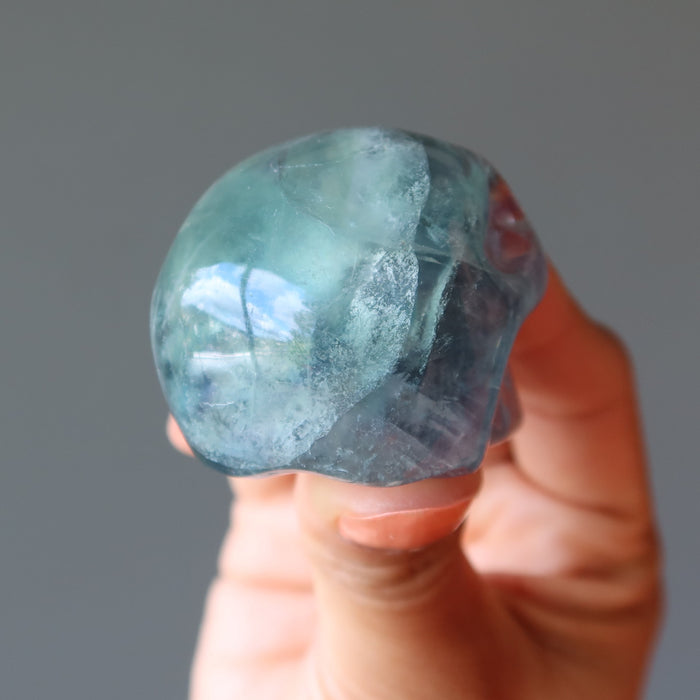 hand holding green purple rainbow Fluorite Skull