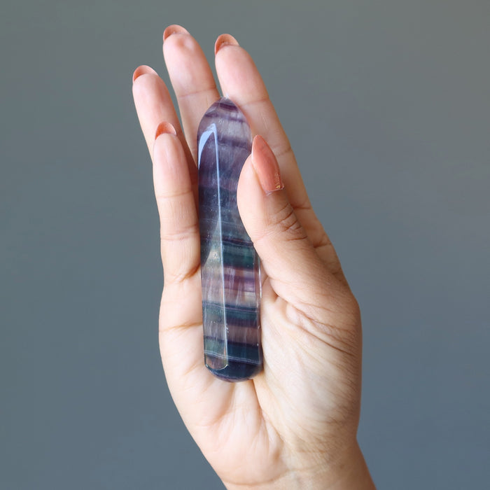 hand holding rainbow fluorite faceted massage wand