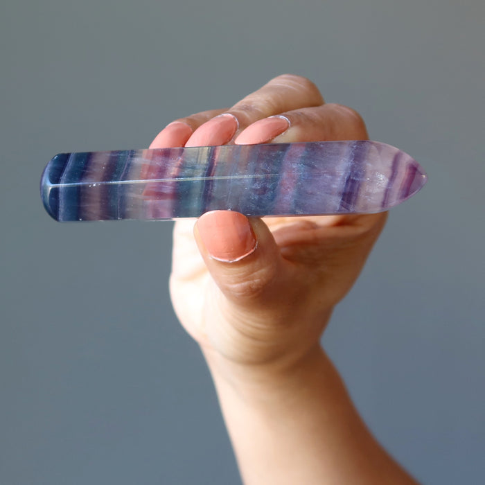 hand holding rainbow fluorite faceted massage wand