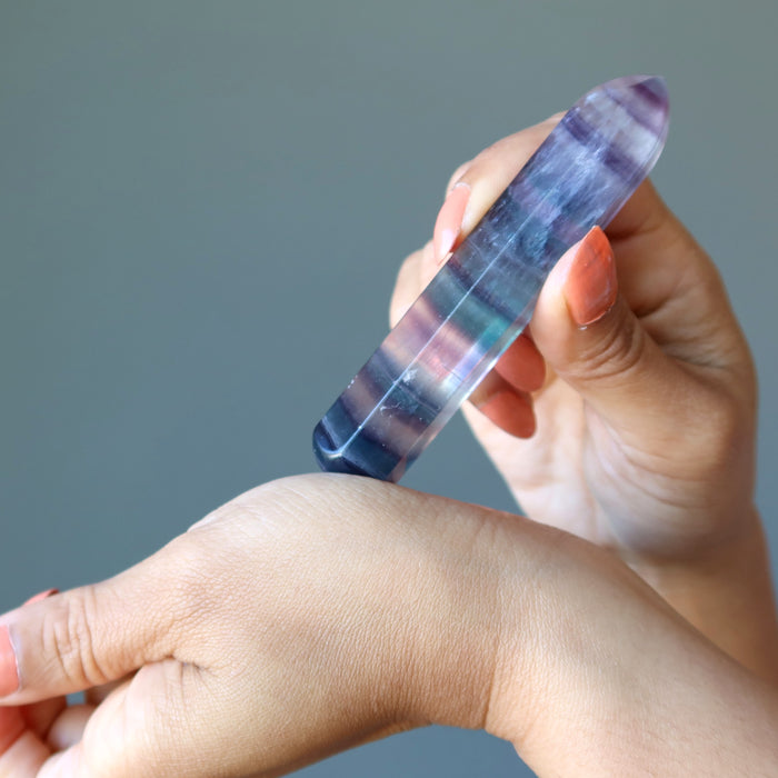 hand holding rainbow fluorite faceted massage wand