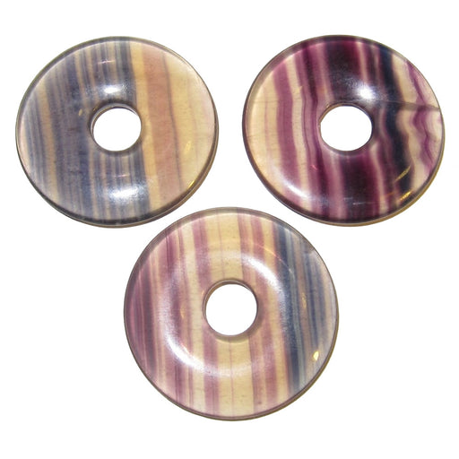 Set of three rainbow Fluorite round donut amulets that are fully polished. They are clear opaque with purple, green, and yellow stripes. Each has a hole in the center for wearing as pendant or using as is.