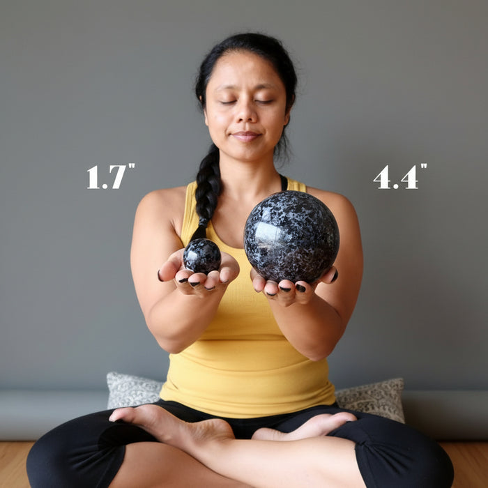 sheila of satin crystals holding 1.7" and 4.4" Indigo Merlinite Gabbro Spheres