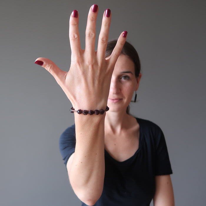 Lucia of satin crystals wearing hand wearing faceted garnet bracelet