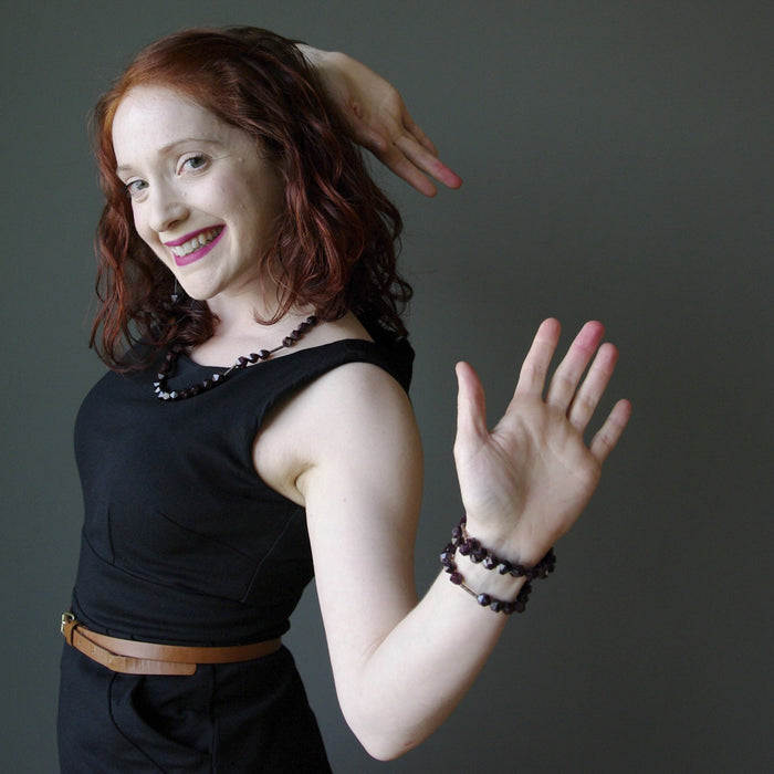 Gemma of Satin Crystals wearing two hand wearing faceted garnet bracelets, garnet earrings and Garnet necklace