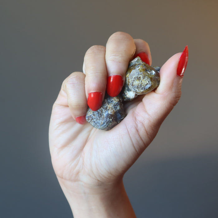 hand holding raw green garnets