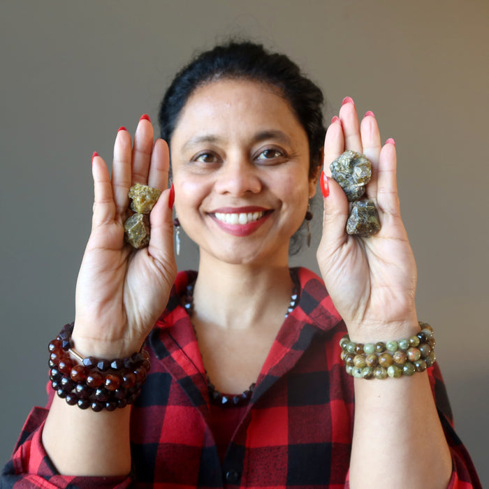 female holding raw green garnet and wearing garnet bracelets