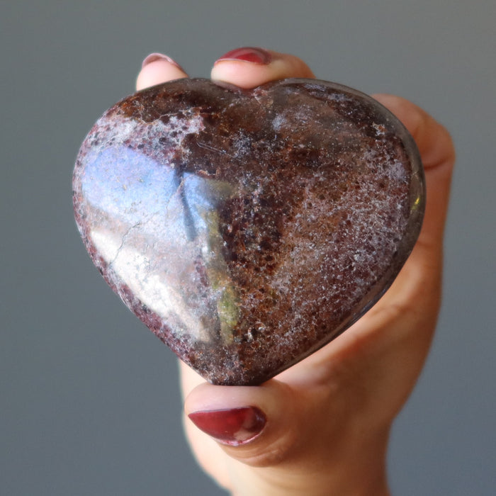 hand holding spotted dark red garnet heart