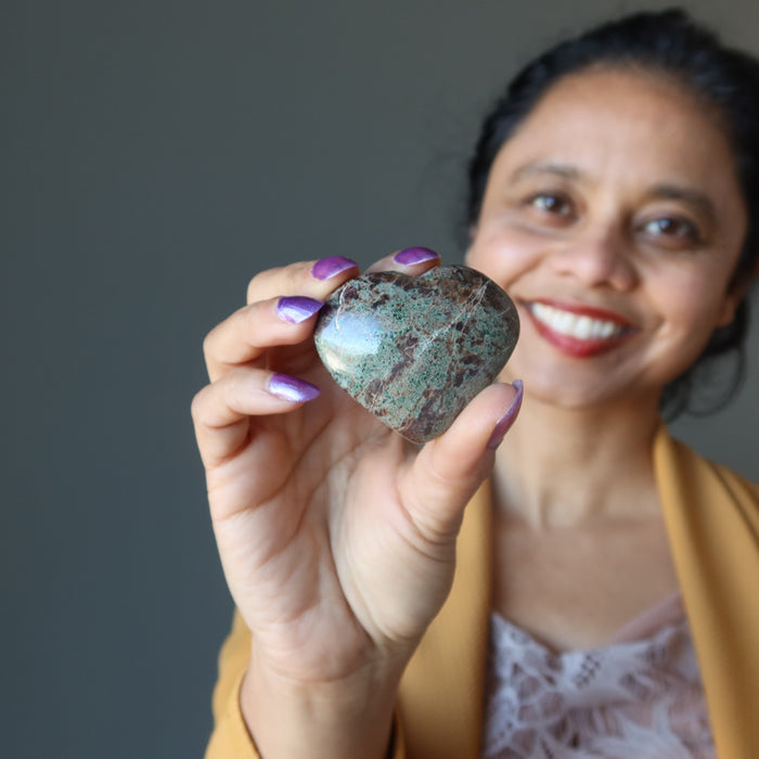 woman holding green and red garnet heart