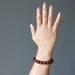 hand wearing hessonite garnet round beaded stretch bracelet