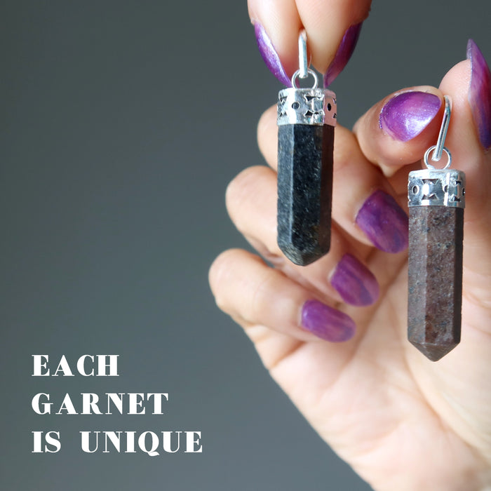 hand holding two garnet point pendants