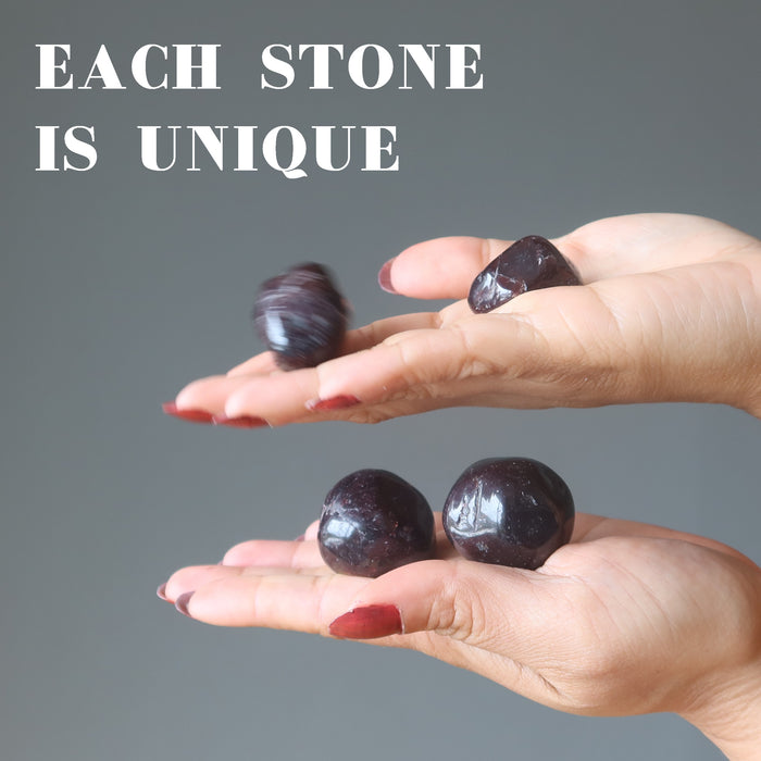 two hands holding pairs of garnet tumbles