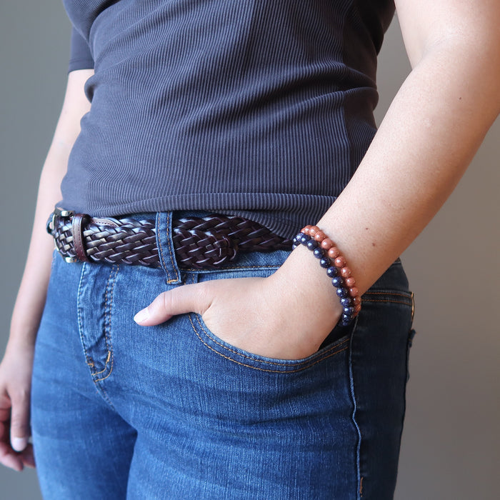 female with hand in jeans pocket wearing goldstone bracelet set