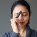 sheila of satin crystals holding a hematite massage wand to her third eye chakra