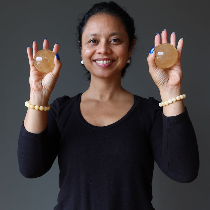 sheila of satin crystals holding up 2 golden calcite spheres