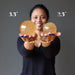 sheila of satin crystals holding out 2 golden calcite sphere to show size difference