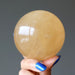 hand holding a honey calcite sphere