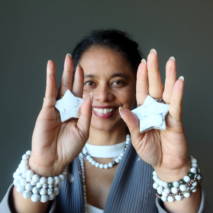 woman holding two howlite stars
