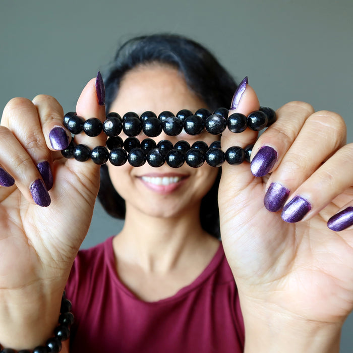 sheila of satin crystals holding up 2 hypersthene bracelets