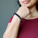 female with hand on chin modeling hypersthene bracelet