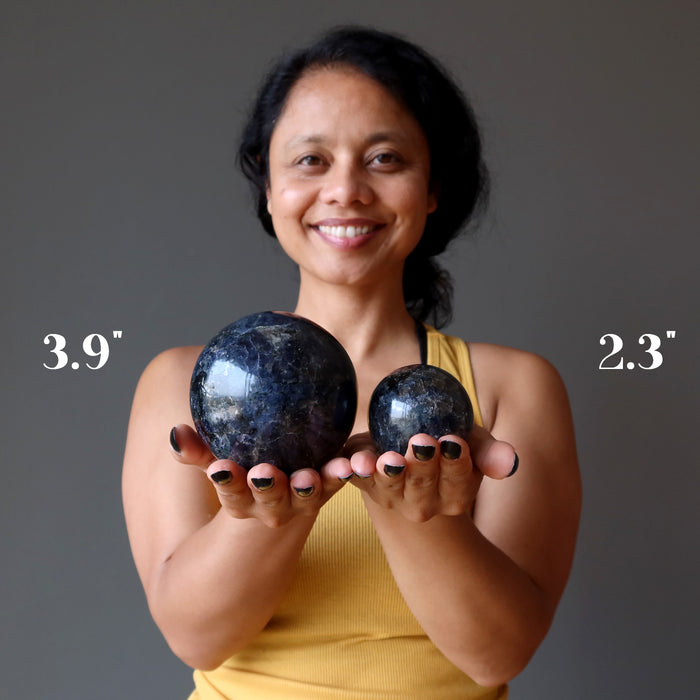 sheila of satin crystals holding two iolite spheres to show size difference