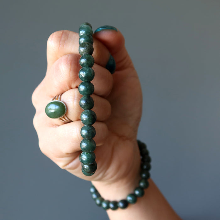 hand holding and wearing dark green jadeite bracelets