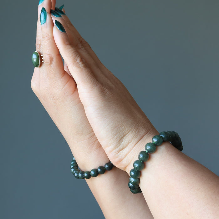 hands wearing dark green jadeite bracelet and ring
