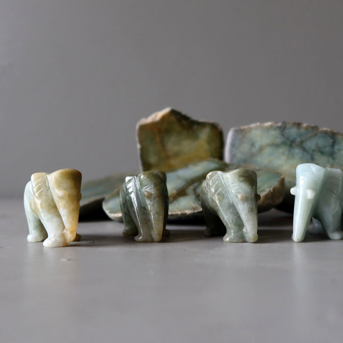 four jade elephants in front of raw jade slabs