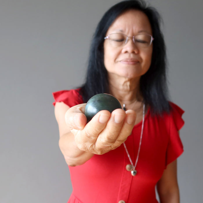 woman meditating with dark green nephrite jade sphere