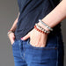 lucia of satin crystals with hands in pockets  wearing set of 3 sesame, red and dalmatian jasper stretch bracelets on each hand.