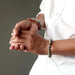 man's hands wearing sesame and red jasper bracelets on one hand and a dalmatian jasper bracelet on the other